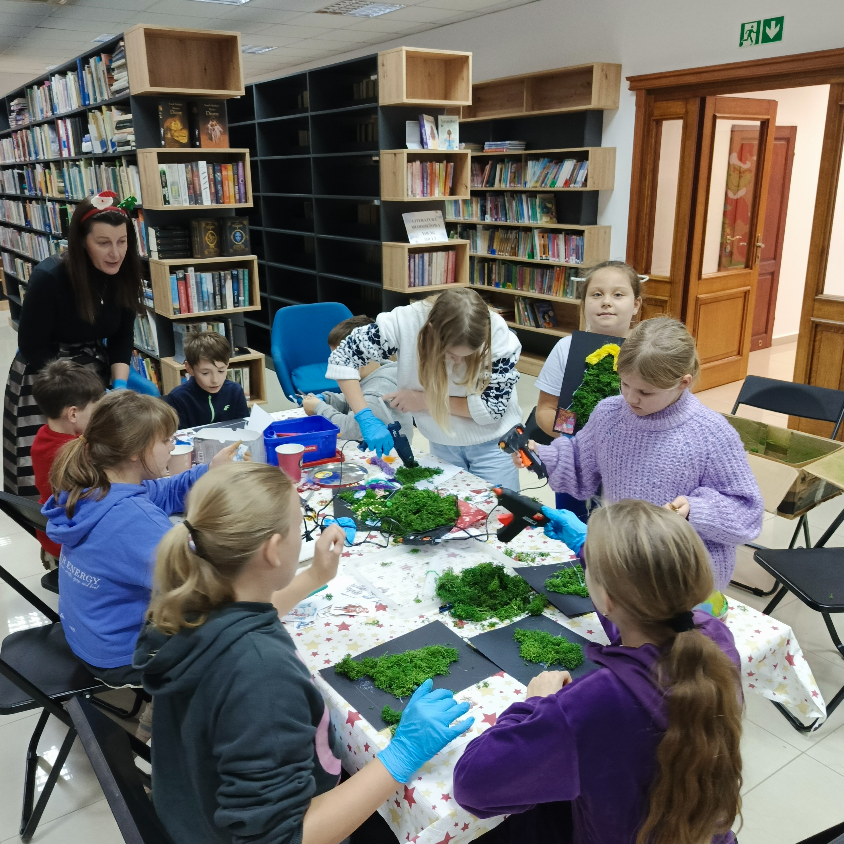dzieci wykonują choinki z chrobotka na warsztatach w bibliotece